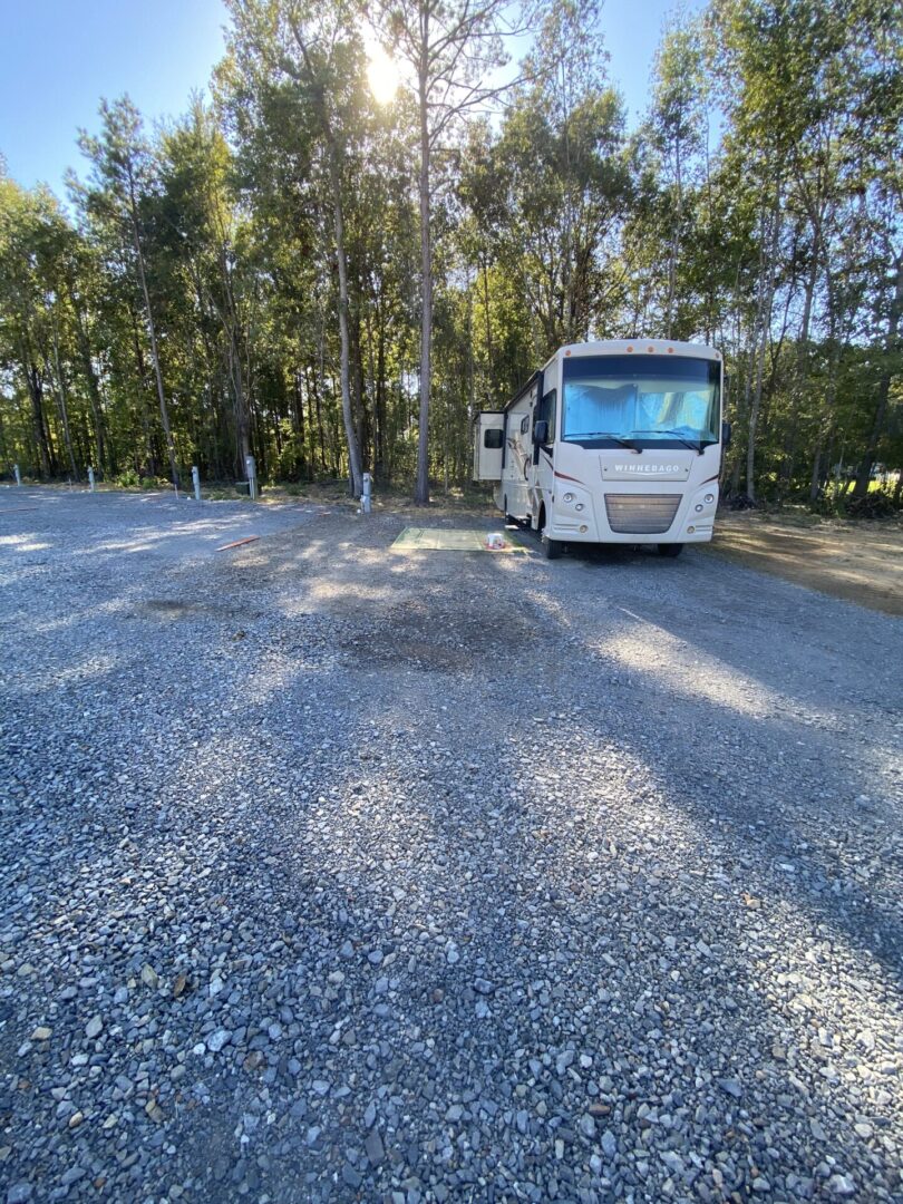 A white bus parked in the middle of a gravel road.