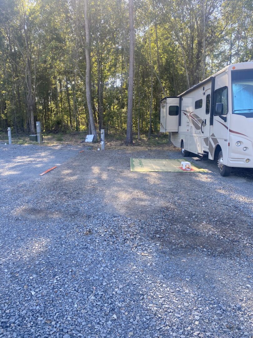 A white rv parked in the middle of a gravel lot.