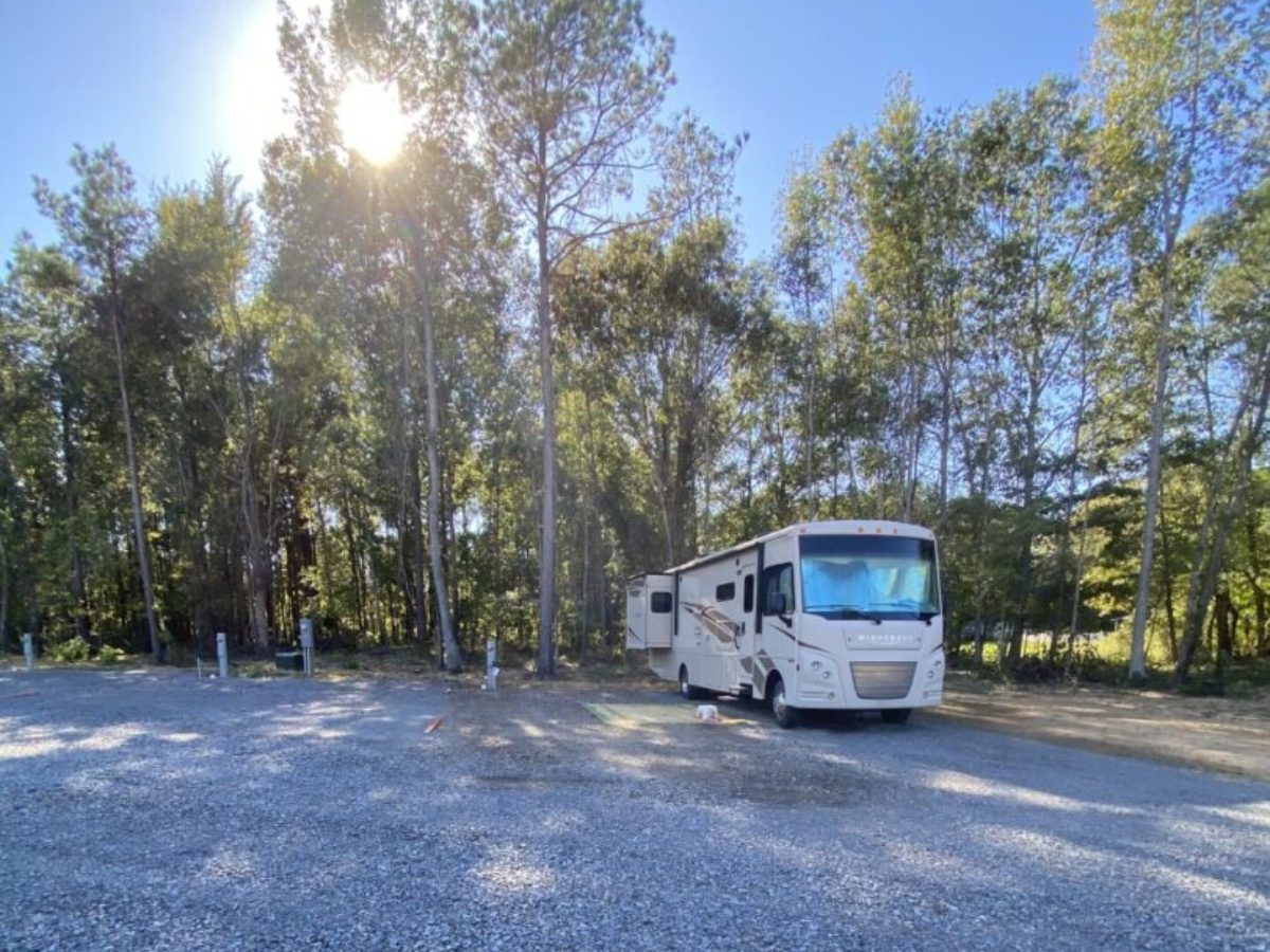 A white rv parked in the shade of some trees.